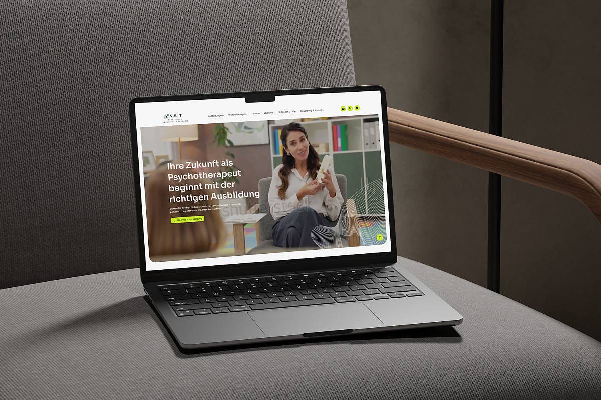 Laptop auf einem grauen Sessel mit geöffneter Website für eine Psychotherapie-Ausbildung.