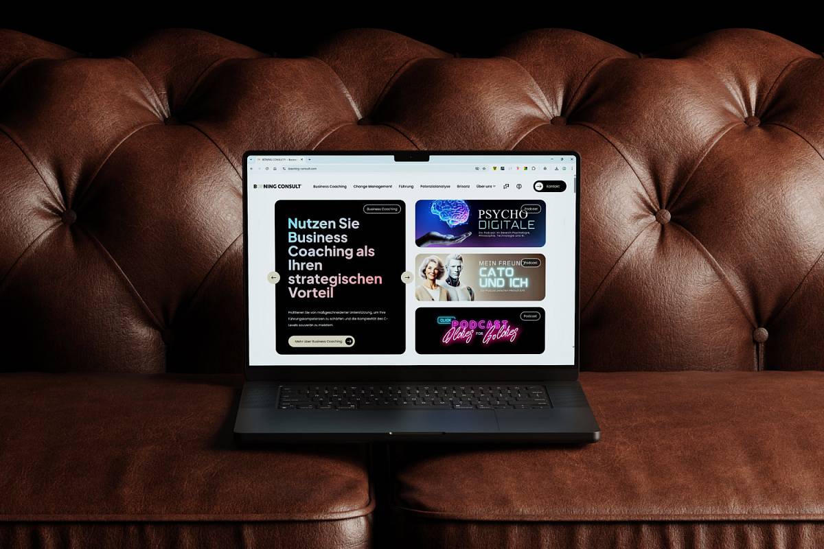 Laptop auf einem braunen Ledersofa mit geöffneter Website für Business Coaching und Podcasts.