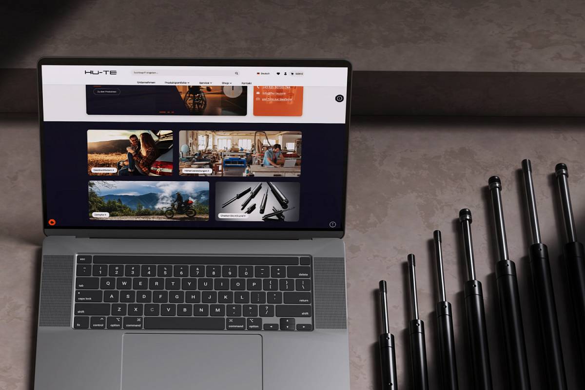 Laptop mit geöffnetem Onlineshop für technische Produkte neben mehreren schwarzen Gasdruckfedern.
