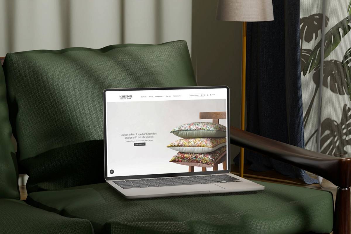 Laptop auf einem grünen Sessel mit geöffnetem Onlineshop für dekorative Kissen.