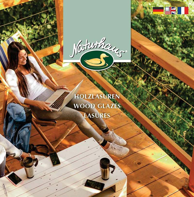 Titelbild von Naturhaus mit einer Frau und Laptop auf einer Holzterrasse sowie dem Hinweis „Holzlasuren – Wood Glazes – Lasures“.